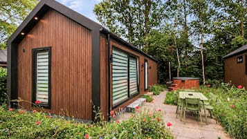 A modern wooden building with large windows and a patio area with outdoor furniture.