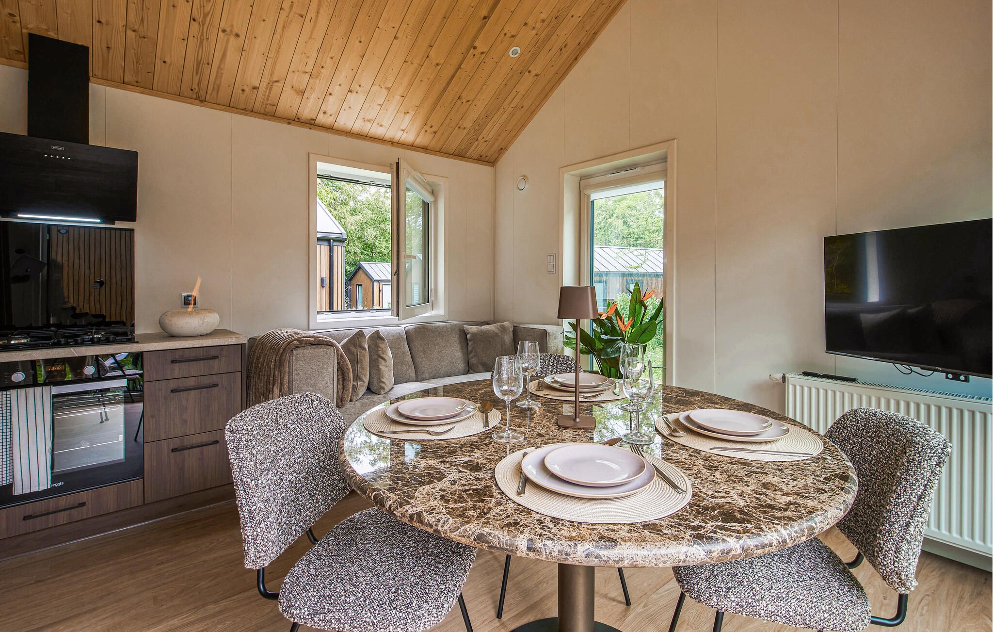 A modern kitchen with a dining area, a TV, and a view of the outside.