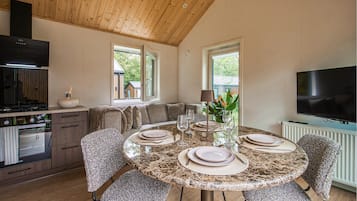 A modern kitchen with a dining area, a TV, and a view of the outside.