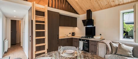A modern kitchen with a built-in stove, a black range hood, and a dining area with a table set for four.