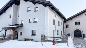 Un edificio de dos pisos con varias ventanas, un muro de piedra y un suelo cubierto de nieve.