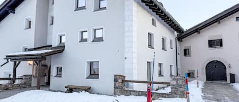 Un bâtiment à deux étages, doté de nombreuses fenêtres, d’un mur en pierre et d’un sol recouvert de neige.
