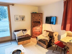 A cozy living room with a brown leather sofa, a wooden cabinet, and a television mounted on the wall. - Muntanella Nuov by Interhome (Sils Maria)