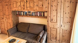 Una habitación acogedora con un armario de madera, una estantería llena de libros y un sofá de cuero marrón.