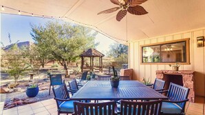 An outdoor patio with a table and chairs, a ceiling fan, and a stone fireplace. - ᔦ-𐌊𐌉𐌍Ᏽ 𐌄𐌍-𐌔𐌵𐌉𐌕𐌄𐌔 + 𝓗Ꝋ𐌕 𐌕𐌵𐌁 (Sedona)