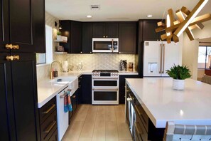 A modern kitchen with dark cabinetry, a stainless steel refrigerator, a built-in microwave, and a double oven. - Luxe Couples Retreat—Indoor Spa * 4 King En-Suites (Sedona)