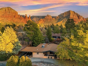 A residential area with a house featuring a covered patio, surrounded by trees and mountains in the background. - Luxe Couples Retreat—Indoor Spa * 4 King En-Suites (Sedona)