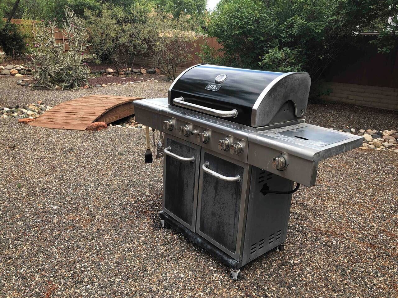 A portable outdoor grill with a built-in smoker, a side burner, and a storage cabinet.