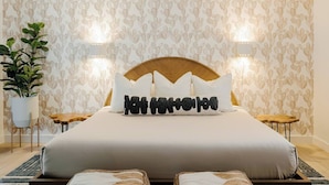 A hotel room with a bed, two bedside tables, a potted plant, and a wall with a cactus pattern. - ᔦ-𐌊𐌉𐌍Ᏽ 𐌄𐌍-𐌔𐌵𐌉𐌕𐌄𐌔 + 𝓗Ꝋ𐌕 𐌕𐌵𐌁 (Sedona)