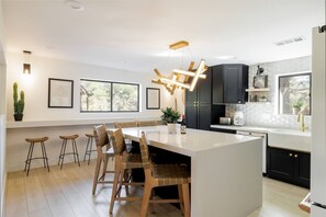A modern kitchen with a central island, bar stools, and a dining area. - Luxe Couples Retreat—Indoor Spa * 4 King En-Suites (Sedona)
