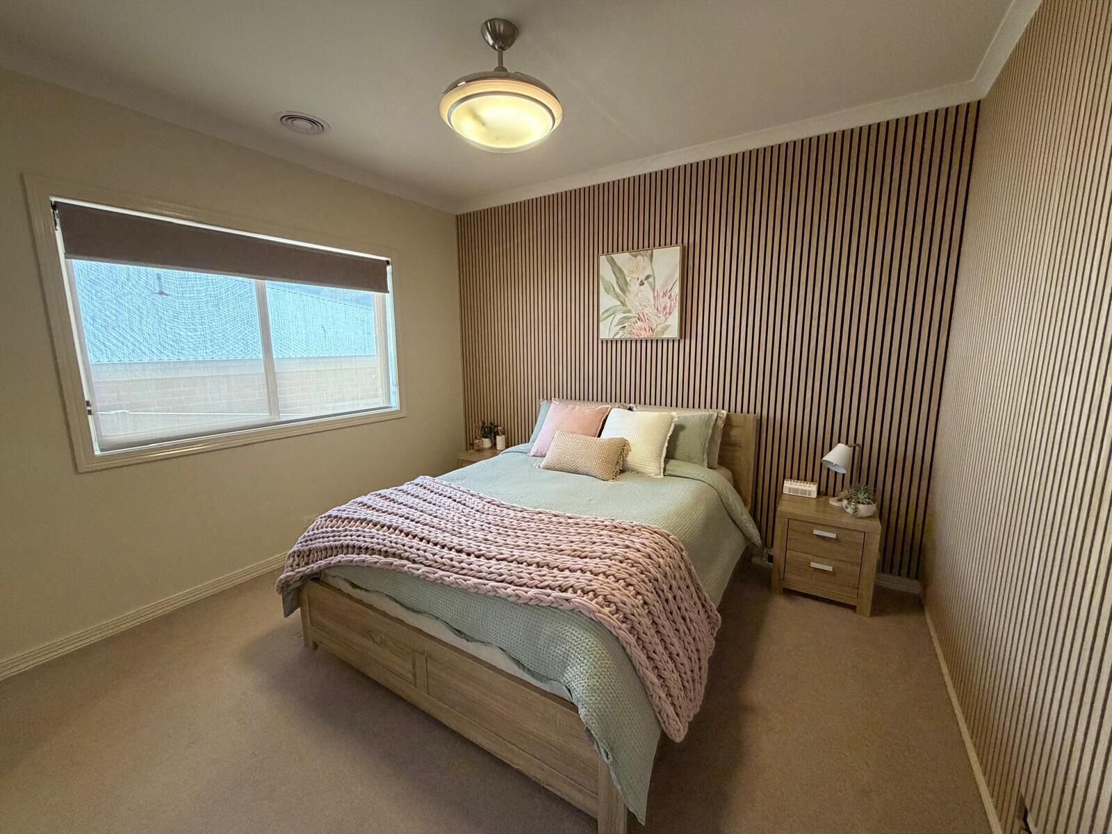 A bedroom with a bed, bedside tables, a window, and a ceiling light.