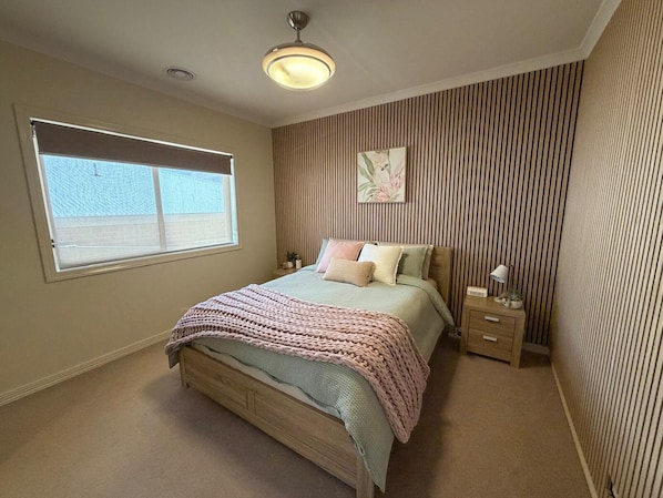 A bedroom with a bed, bedside tables, a window, and a ceiling light.
