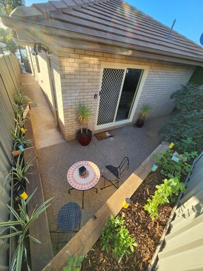 A residential backyard with a patio area, a sliding glass door, and potted plants. - Just Opened! The Nest at Forest Lake - Stylish Guest Suite (Kangaroo Flat)