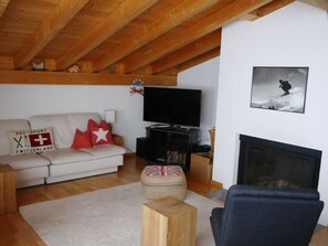 A living room with a sofa, television, fireplace, and a ski-themed pillow. - Mira Selva, (Flims Dorf), by Interhome (Flims)