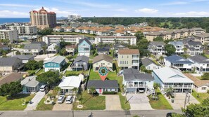 A residential area with multiple two-story houses, a large building in the background, and a body of water. - Sea La Vie | Coastal Comfort by the Beach (North Myrtle Beach)
