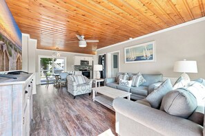A spacious living area with a wooden ceiling, a dining area with a view, and a kitchen with modern appliances. - Sea La Vie | Coastal Comfort by the Beach (North Myrtle Beach)