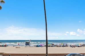 A beach with a lifeguard tower, umbrellas, and people. - TRUE Oceanfront • Steps to Beach • Pool 205A (Oceanside)