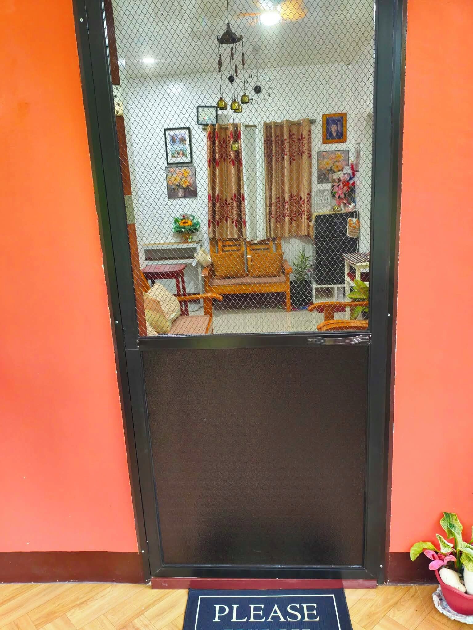 A room with a bed, a chair, a table, and a plant.