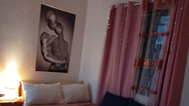 Ein Schlafzimmer mit einem Bett, Kissen, einem Nachttisch, einer Lampe und einem Wandbild.