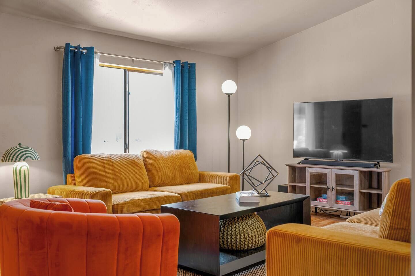 Una sala de estar con sofá, sillón, mesa de centro y televisor de pantalla plana.