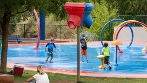 Área de recreação com água ao ar livre, com diversos recursos aquáticos e um gramado para sentar.