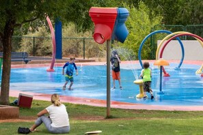 Ein Wasserpark im Freien mit verschiedenen Wasserspielen und einer Rasenfläche zum Sitzen.