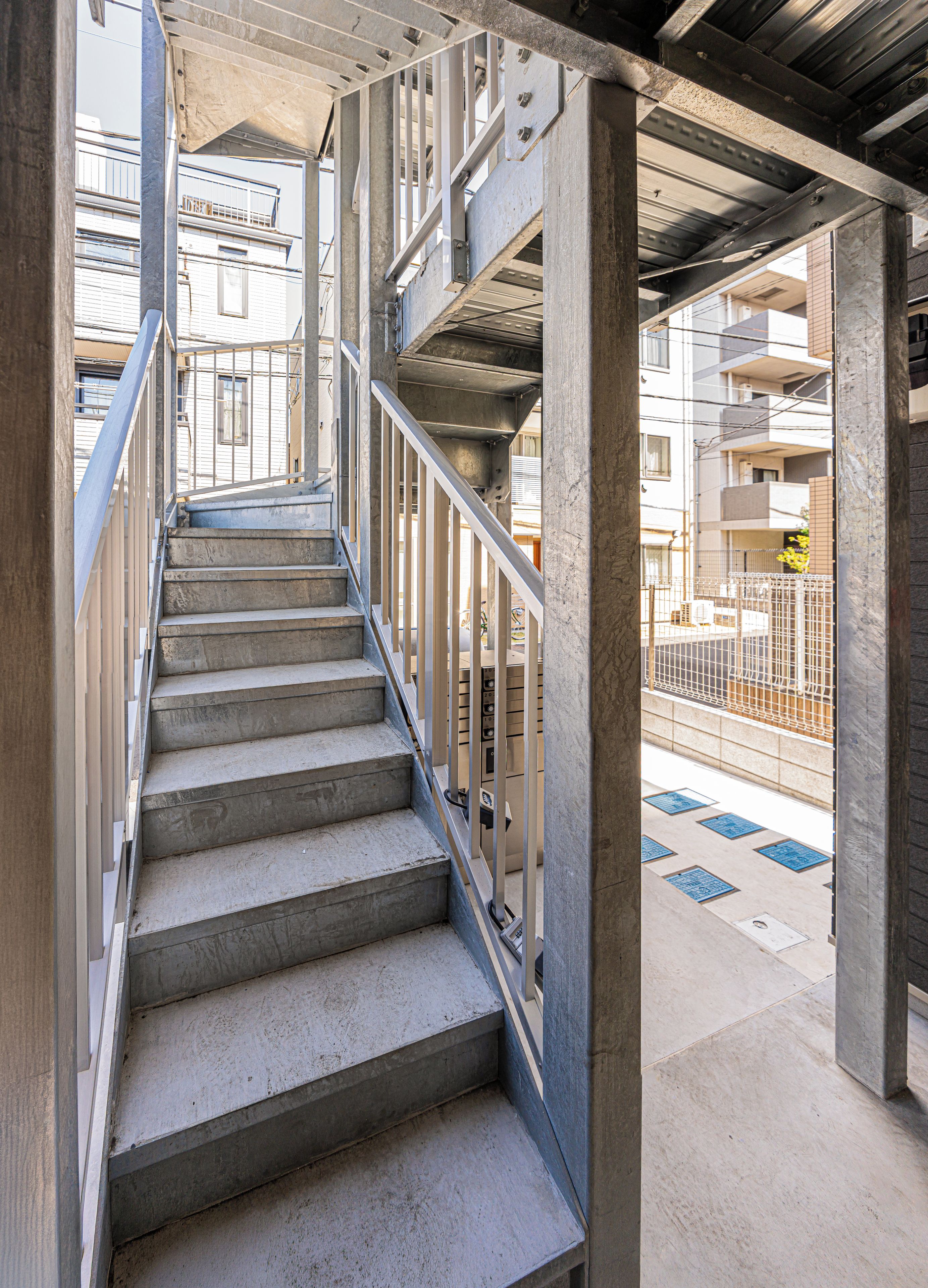 Un escalier en béton avec des rampes métalliques menant à un niveau supérieur.