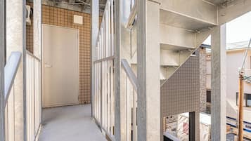 A narrow corridor with metal railings, a concrete floor, and a door at the end.