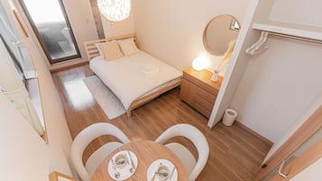 Een kleine slaapkamer met een bed, nachtkastje en spiegel.