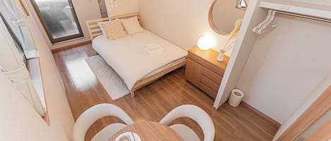 A compact bedroom with a bed, bedside table, and a mirror.