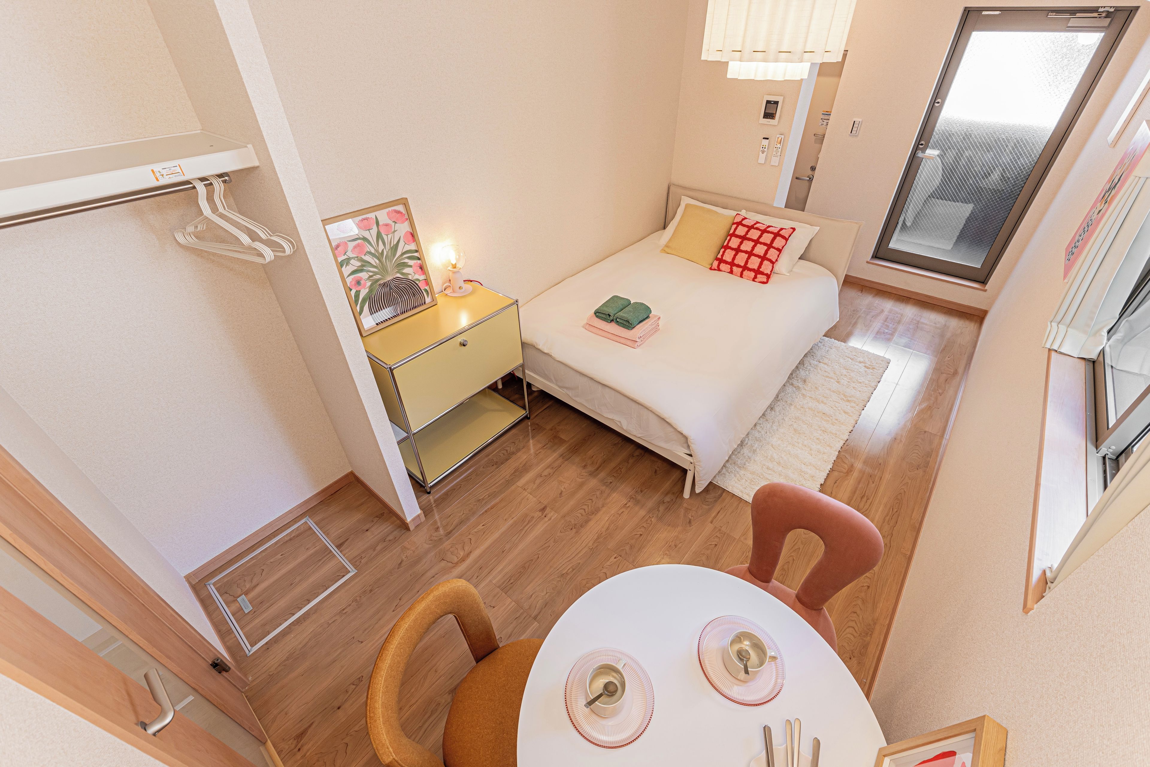 Een kleine hotelkamer met een bed, nachtkastje en een eettafel.