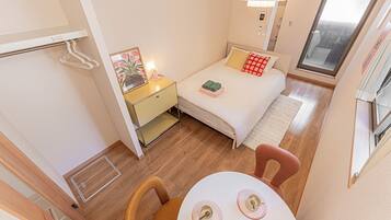 Een kleine hotelkamer met een bed, nachtkastje en een eettafel.