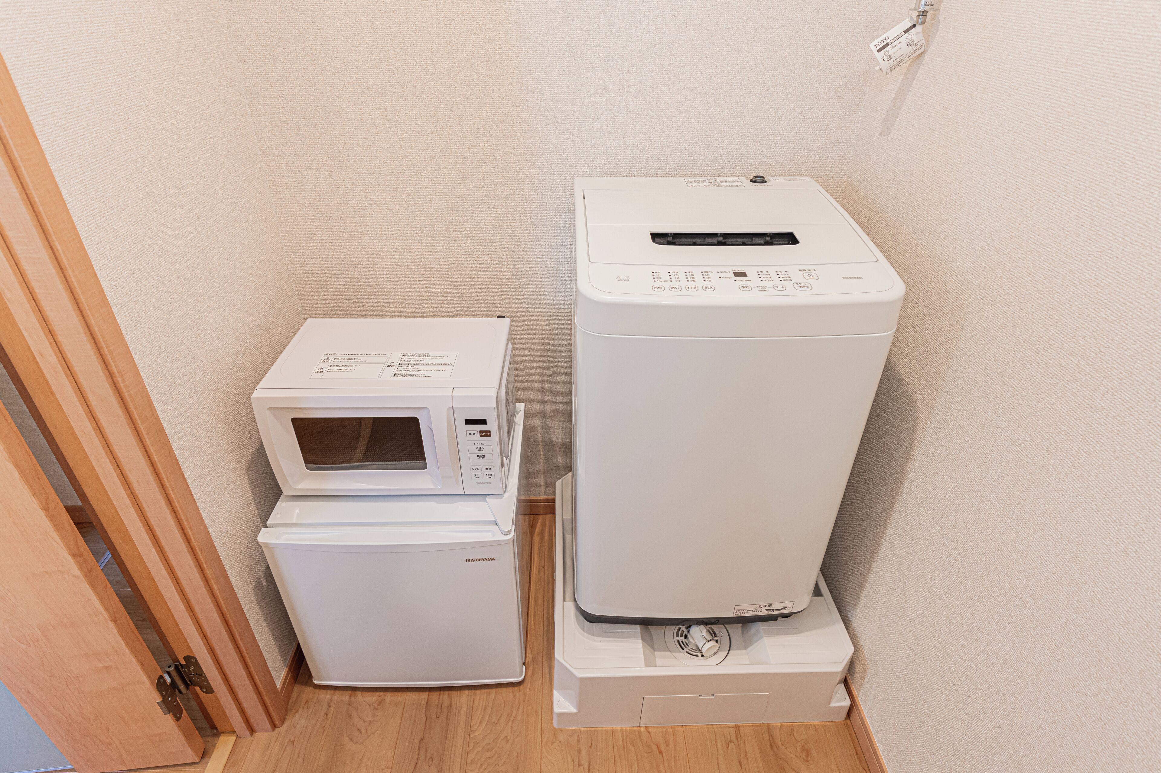 Une petite buanderie équipée d’un four à micro-ondes, ainsi que d’un lave-linge et d’un sèche-linge superposés.