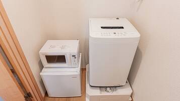 Une petite buanderie équipée d’un four à micro-ondes, ainsi que d’un lave-linge et d’un sèche-linge superposés.