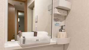 A bathroom with a toilet paper holder, a hand soap dispenser, and a mirror. - The Parknest Haneda (Tokyo)