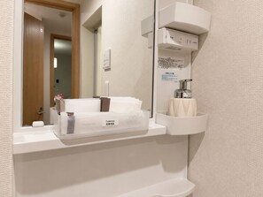 Casa de banho com suporte de papel higiénico, dispensador de sabonete líquido e espelho.
