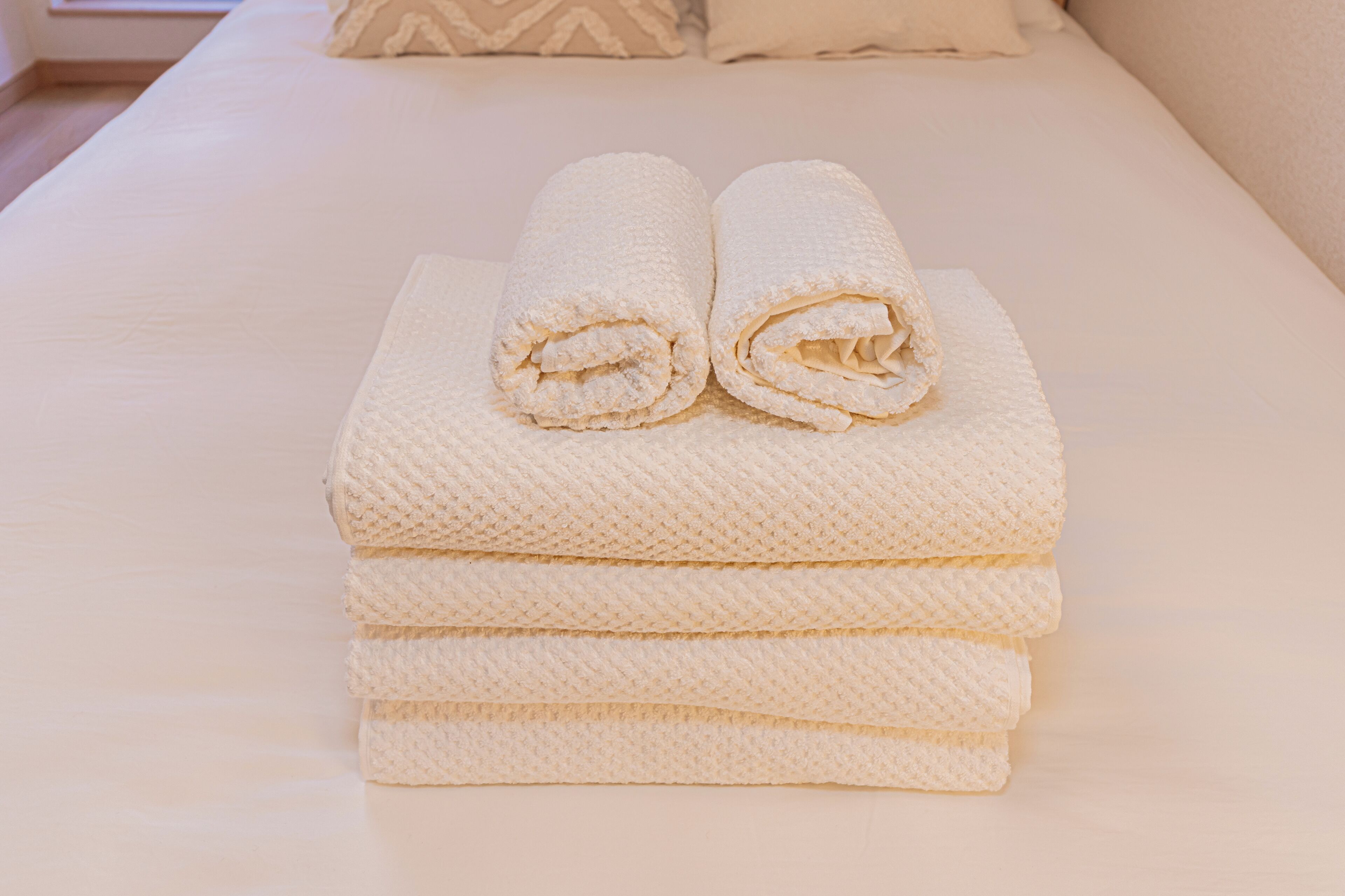 A neatly made bed with a white mattress and a pillow with a geometric pattern.