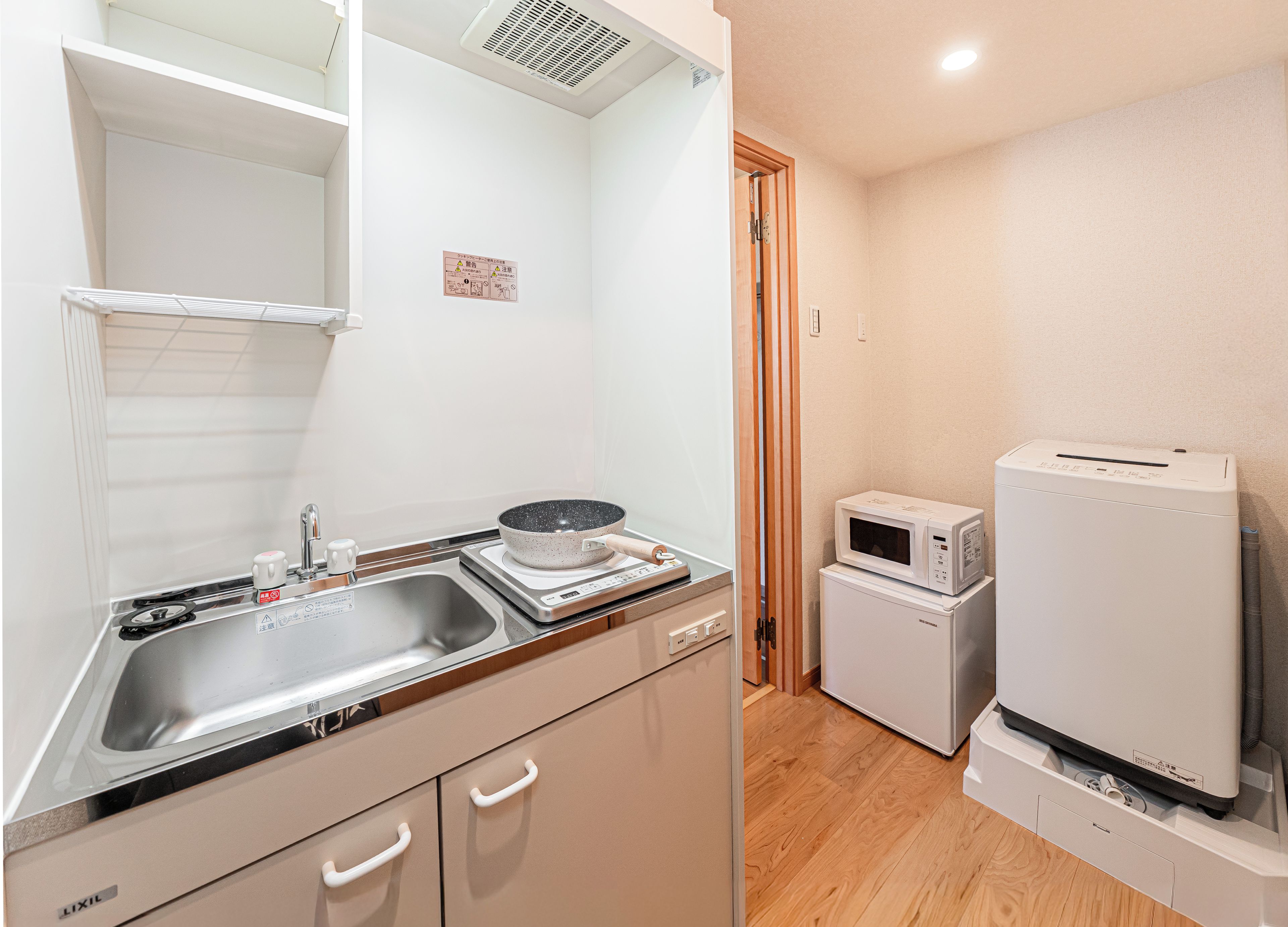 A compact kitchen with a sink, stove, microwave, and a small refrigerator.