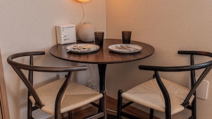 A round dining table with two chairs, a wall-mounted light fixture, and a small table lamp. - The Parknest Haneda (Tokyo)