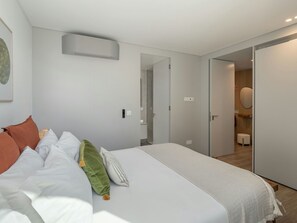 Ein modernes Schlafzimmer mit einem großen Bett, einem Nachttisch, einem Spiegel und einer Tür zu einem Badezimmer.