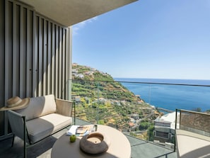 A balcony with a sofa, a hat, a bowl, and a book. - Azure Calheta by Interhome (Calheta (Madeira))