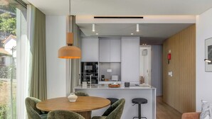 Een moderne keuken met een centraal eiland, een eetgedeelte met een ronde tafel en stoelen, en een zithoek met een bank en salontafel.