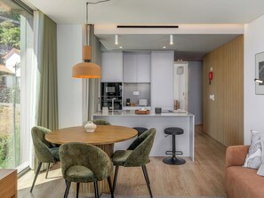 A modern kitchen with a central island, a dining area with a round table and chairs, and a living area with a sofa and a coffee table. - Azure Calheta by Interhome (Calheta (Madeira))