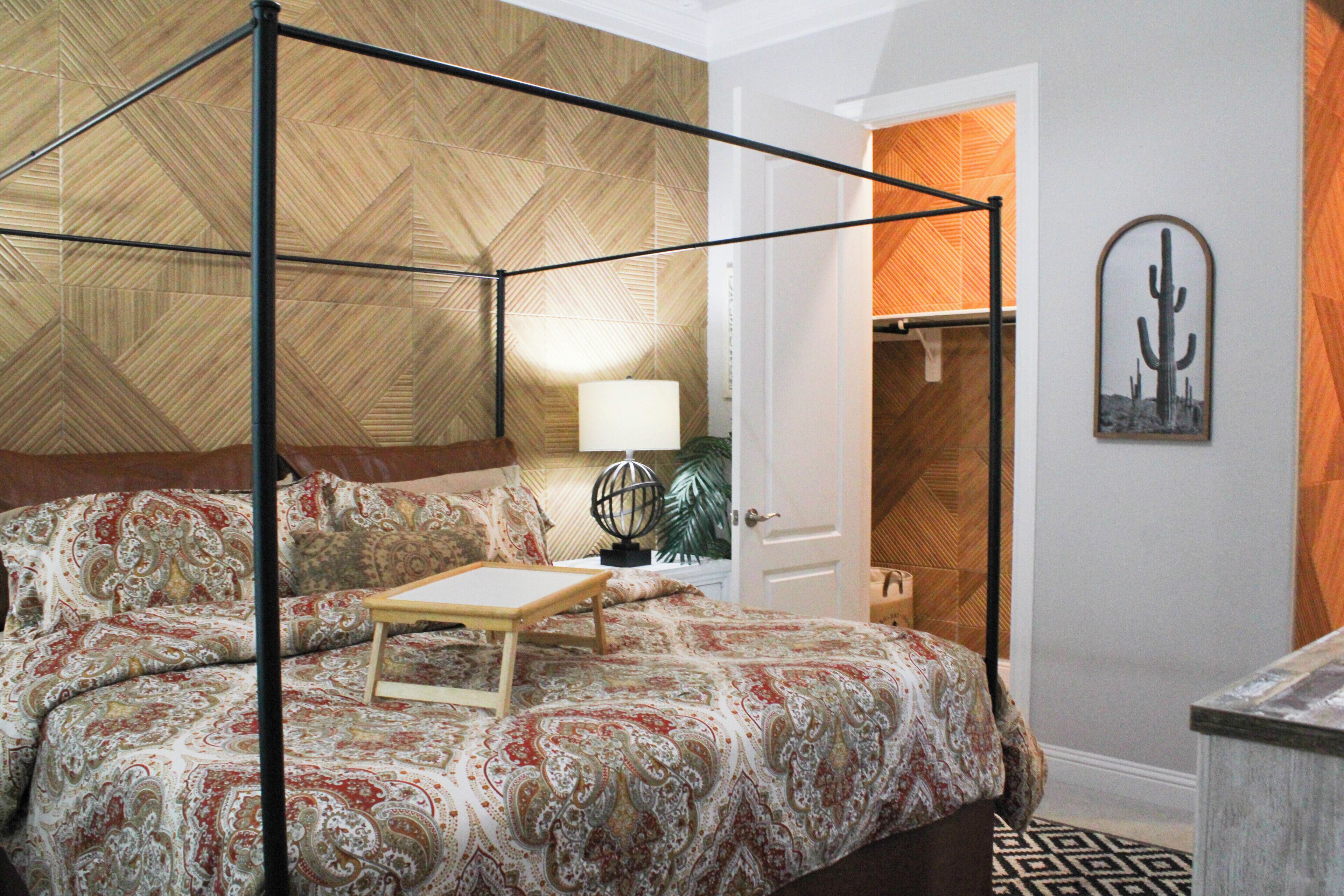 Une chambre à coucher avec un lit à baldaquin, une table de chevet avec une lampe et une porte donnant sur une salle de bain.