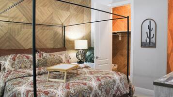 Une chambre à coucher avec un lit à baldaquin, une table de chevet avec une lampe et une porte donnant sur une salle de bain.