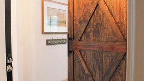 Una porta in legno in stile fienile con elementi di rinforzo incrociati, una panca, un punto luce a parete e un tappeto decorato.
