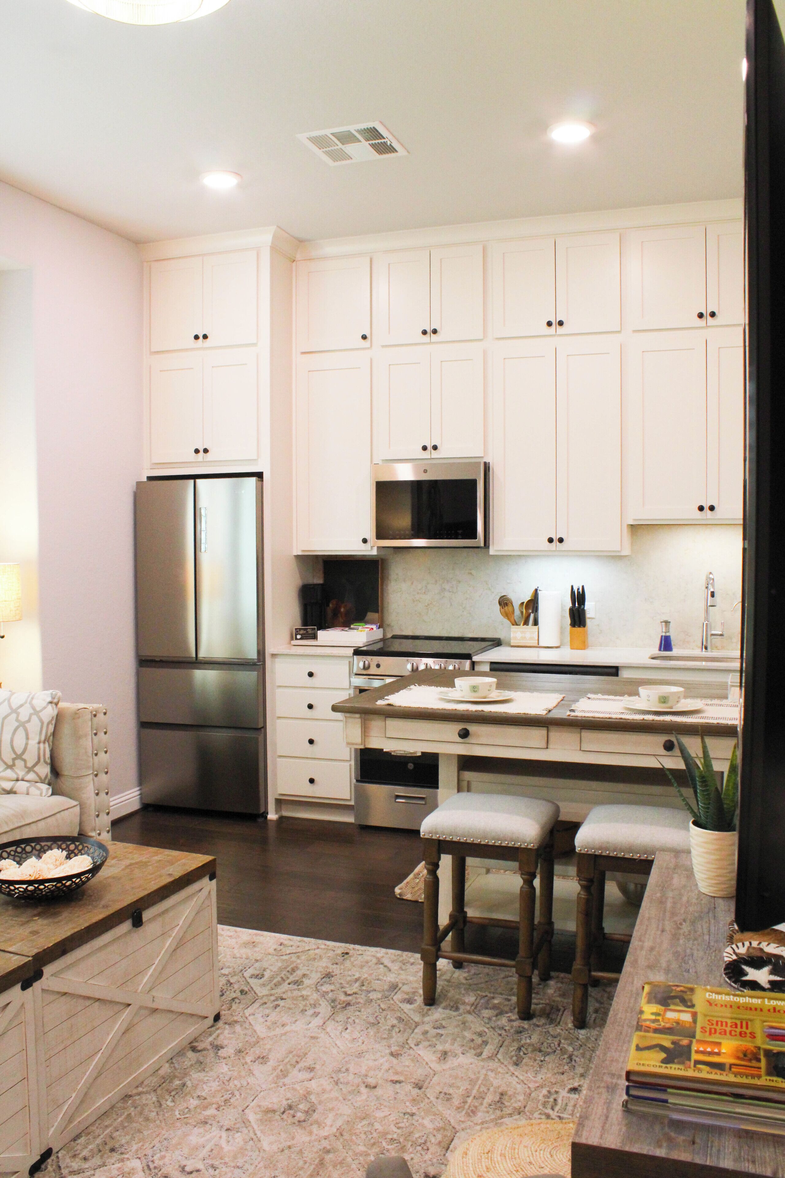 A modern kitchen with white cabinets, stainless steel appliances, and a dining area with a wooden table and chairs.