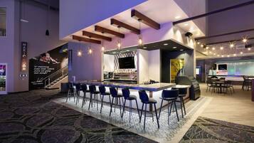A modern bar area with a long counter, bar stools, and a television screen.