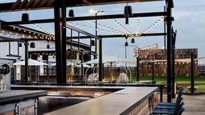 Zona bar all'aperto con un bancone, posti a sedere e luci decorative a tenda.