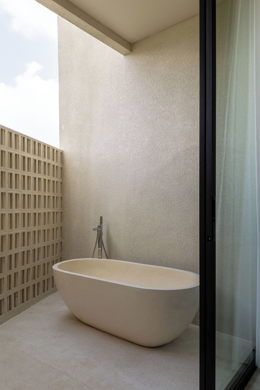 A modern bathroom with a freestanding bathtub, a glass shower enclosure, and a concrete floor.